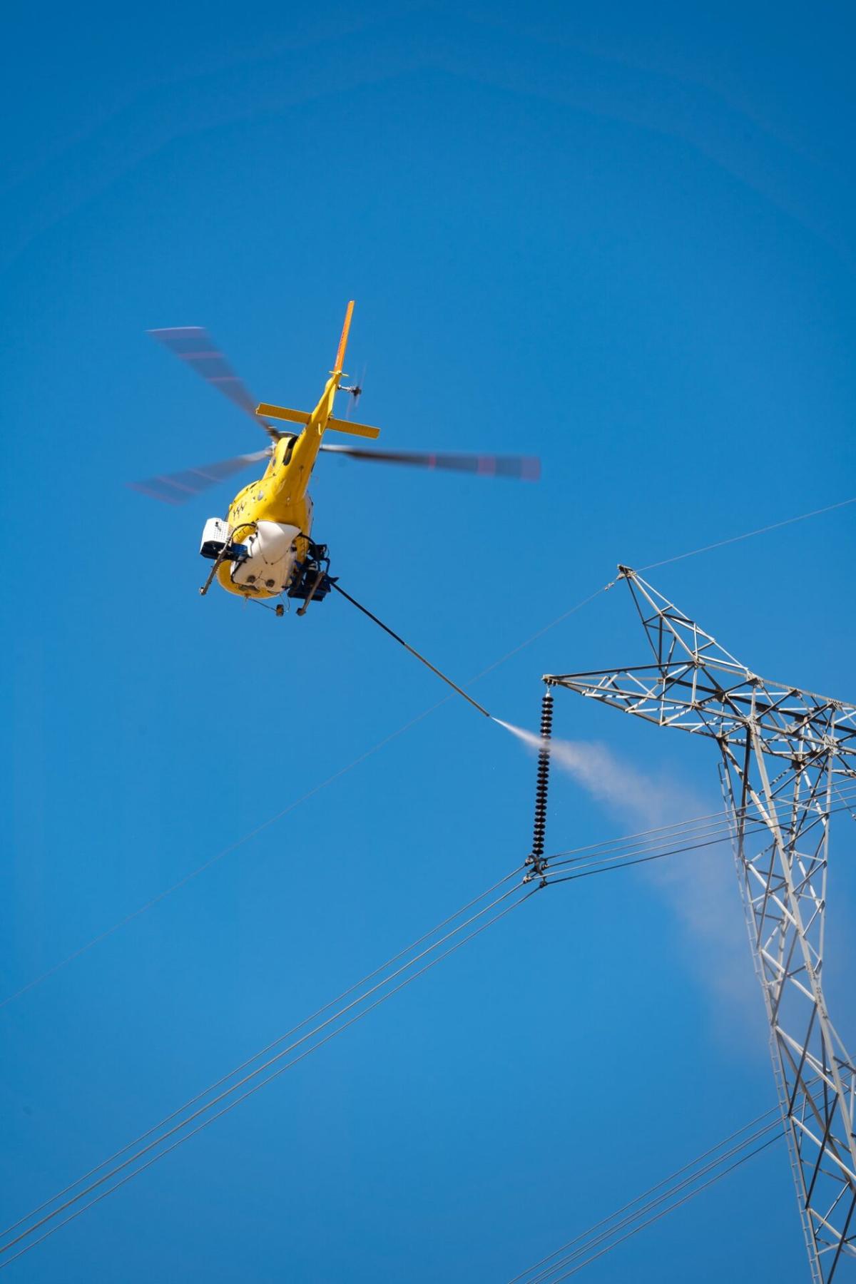 Usan helicópteros y agua a presión para limpiar los aisladores de las grandes torres eléctricas