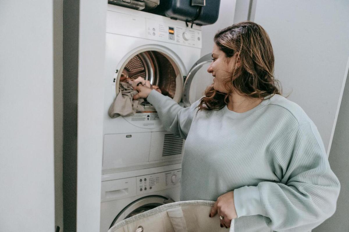 Una mujer saca la ropa de la secadora. 