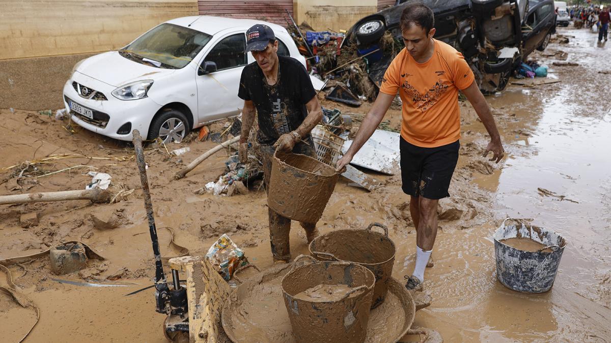 Vecinos de Paiporta limpian el lodo de una calle afectada, este viernes.