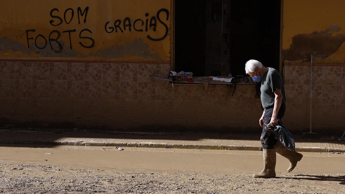 Un hombre camina por una calle embarrada en Paiporta (Valencia) este lunes. 