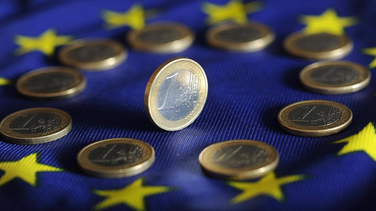 Monedas de euro sobre una bandera del euro.