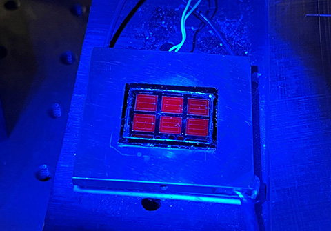 La celda solar que establece récords brilla en rojo bajo una luminiscencia azul. Foto: Wayne Hicks, NREL