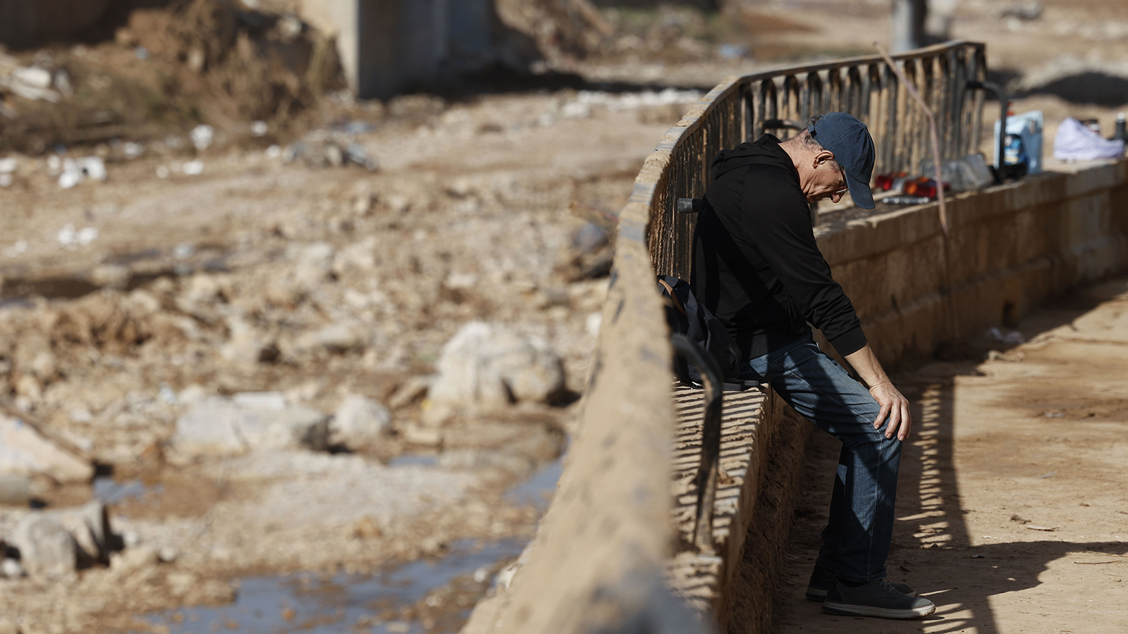 Un hombre toma un descanso junto al barranco del Poyo a su paso por Paiporta, este lunes. 