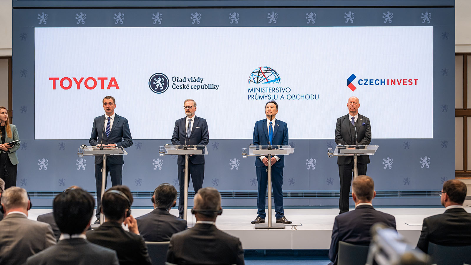 oshihiro Nakata, presidente y consejero delegado de Toyota Motor Europe junto con Petr Fiala, primer ministro de la República Checa, y Lukáš Vlček, ministro de Industria y Comercio, República Checa, durante el anuncio del nuevo vehículo eléctrico de batería que será producido en Europa. - Toyota /></p><p>La firma nipona tiene una <strong>larga historia en la República Checa</strong> y su presencia como fabricante se remonta a más de dos décadas, durante las que ha <strong>producido más de 4,5 millones de vehículos</strong>. El primero modelo en salir de la línea de montaje fue el Aygo en 2002 y en la actualidad fabrica el Aygo X Cross y el Yaris Hybrid, con una capacidad de unos 220.000 vehículos anuales. La introducción de la producción de BEV aumenta el potencial de capacidad de la planta y su estrategia multitecnología, y dará lugar al crecimiento del empleo directo, que se extenderá a la cadena de suministro, ya que la <strong>mayoría de los componentes tendrán su origen en la misma República Checa.</strong></p>
<blockquote><p>Relacionado:</p><p><a href=