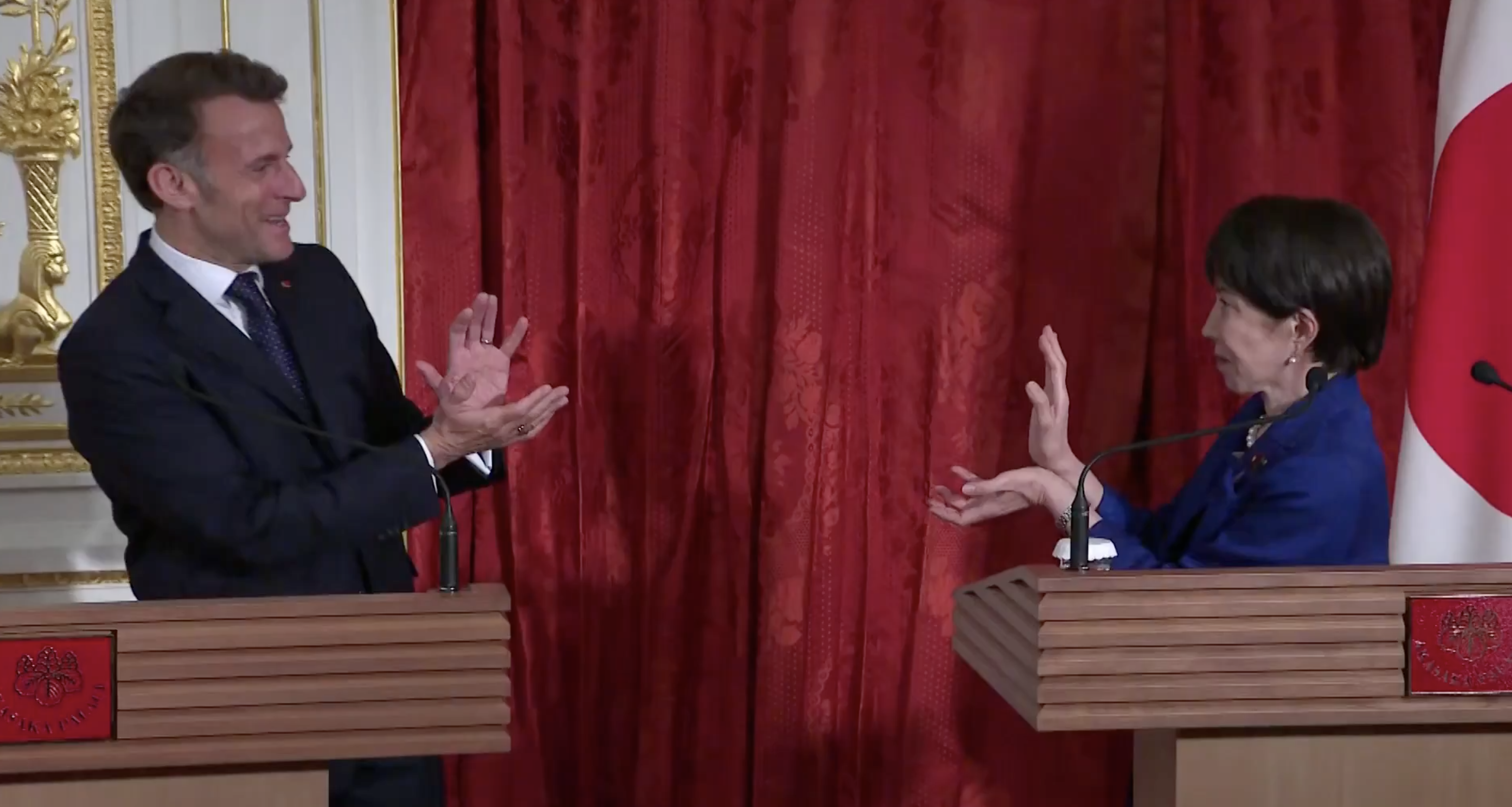 Macron y la primera ministran nipon hacen el gesto de 