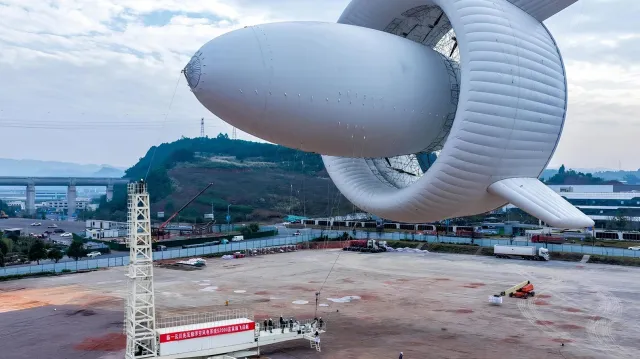  /></p><p>El artefacto ascendió durante 30 minutos hasta los 2.000 metros sobre la provincia de Sichuan, donde los vientos son más estables y potentes. Allí generó 385 kWh que se inyectaron directamente a la red de microensayo mediante un cable de amarre que también transmite la electricidad. La empresa afirma que su capacidad máxima alcanza los 3 MW y que una hora de operación puede cargar completamente 30 vehículos eléctricos de alta gama.</p>
<p>Según Jianxiao Wang, profesor de la Universidad de Pekín involucrado en el proyecto, "utilizamos hasta un 90% menos de material que las turbinas tradicionales. No necesitamos cimientos de hormigón, ni torres de acero, ni alteramos el ecosistema del suelo. El impacto visual y sonoro es mínimo: es prácticamente silencioso a nivel del suelo".</p>
<p>Además, la empresa asegura que el S2000 puede transportarse en contenedores estándar y desplegarse en unas ocho horas, lo que lo hace ideal para zonas de desastre, puestos fronterizos aislados o cualquier ubicación donde la construcción de una torre convencional sea inviable. La compañía ya acumula pedidos por valor de casi 500 millones de yuanes (73 millones de dólares) para sus plataformas S1500 y S2000, y tiene en desarrollo los modelos S4000 y S6000, este último destinado a alcanzar la estratosfera.</p>
<h3>Luces y sombras de una tecnología aún inmadura</h3>
<p>Pero no todo es optimismo. El profesor Mark C. Kelly, de la Universidad Técnica de Dinamarca, advierte que no ha visto datos revisados por pares sobre la producción real del SAWES por encima de los 1.000 metros. "Cómo se comporta el viento por encima de los 100 metros no es sencillo", señala. La fiabilidad del cable de amarre de 2 kilómetros en condiciones de tormenta o su interferencia con el espacio aéreo civil son interrogantes mayúsculos. El historial de los sistemas eólicos aerotransportados está lleno de prototipos prometedores (como el Makani de Google) que nunca lograron ser comerciales.</p>
<p>Además, la disponibilidad y el coste del helio (un recurso finito y cada vez más caro) podrían convertirse en un cuello de botella. Por último, el mantenimiento de un artefacto que debe regresar a tierra para cada reparación podría encarecer su operación frente a una turbina convencional. El próximo hito no es volar más alto, sino demostrar meses de operación continua con un factor de carga y un coste por kWh competitivos.</p>
<h3>Geopolítica y resistencia comercial</h3>
<p>Mientras China acelera en estos tres frentes, Occidente mira con inquietud. La administración Trump no solo ha frenado más de 150 proyectos eólicos al retrasar las revisiones militares, sino que ha destinado 2.000 millones de dólares a compensar a empresas que abandonan parques marinos. La Unión Europea ha abierto una investigación antisubvención a Goldwind (el mayor fabricante mundial) y Reino Unido bloqueó a Ming Yang la instalación de turbinas en sus aguas por seguridad nacional. Pekín ya ha condenado estas decisiones, augurando represalias.</p>
<blockquote><p>Relacionado:</p><p><a href=